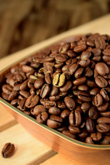 Golden roasted coffee bean among the others in a wooden bowl