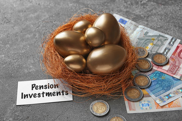Golden eggs in nest, money and sign PENSION INVESTMENTS on grey background