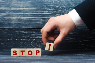 The hand holds a cube with the exclamation point symbol for the word stop. The concept of warning,...