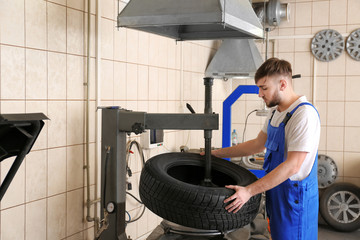 Mechanic changing car tire in service center