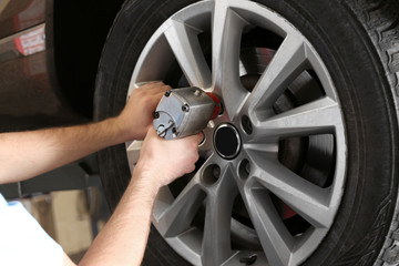 Mechanic changing car wheel in garage. Tire service