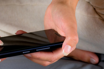 Woman sitting on bed and writing message on cellphone.