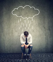 Fotobehang Sad business man sitting on a chair looking down with a rain cloud above him © pathdoc