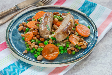 Sausage and bean casserole with carrots and green peas - top view