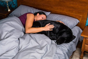 Woman sleeping in bed with dog.