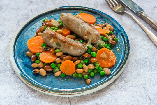Sausage and bean casserole with carrots and green peas - top view