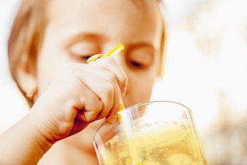 Little cute girl drinking tasty natural smoothie juice outdoors. (children's food, healthy...