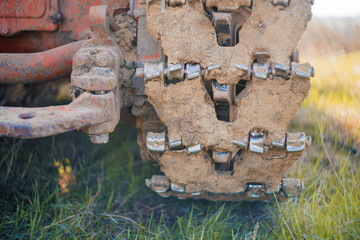 Close up muddy continuous caterpillar tracks of the bulldozer n a background of green grass