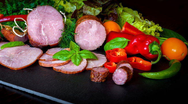 Smoked sausage with lettuce and tomatoes on wooden board