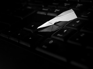 Online Flight a small paper aeroplane on a computer keyboard