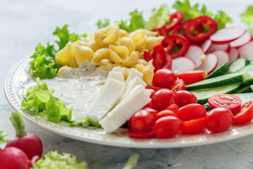 Vegetable salad with pasta and fresh cheese.