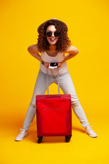 Woman traveler with suitcase on color background.