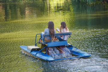 Two girls ride on catamaran on the lake. Vacation