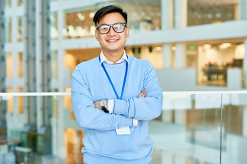 Waist-up portrait of smiling Asian white collar worker posing for photography with arms crossed...