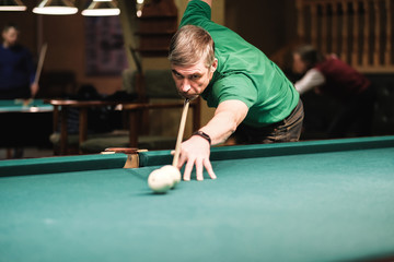 a pool player takes aim at the ball