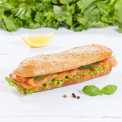 Sub sandwich whole grains baguette with smoked salmon fish square on wooden board