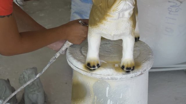 Woman hand in glove paint pug dog statue details by airbrush 