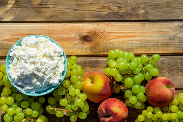 Plate of homemade cottage cheese, grapes and peach on wooden rustic table.Copy space for text.