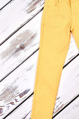 Girls yellow skinny trousers. Female skinny colored jeans on white wooden background. Woman summer fashion style.