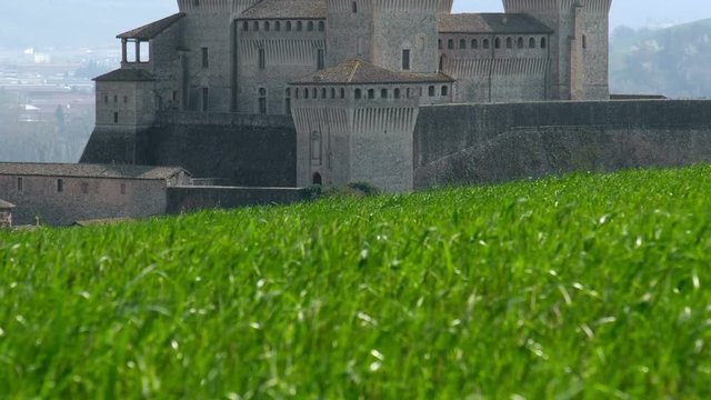 castle of Torrechiara in Parma, Italy through windy meadow grass panorama - Emilia Romagna region vertical panning