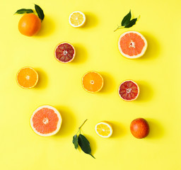 Fresh citrus fruits split on yellow background.