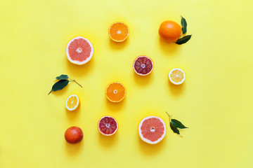 Fresh citrus fruits split on yellow background.