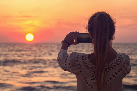 A girl takes a picture of the sunset