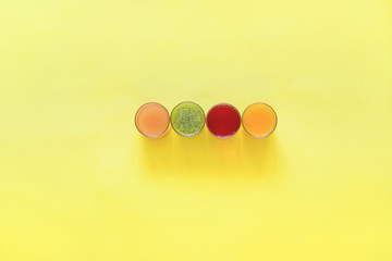 Fresh juices and fruit cut into slices on a yellow background