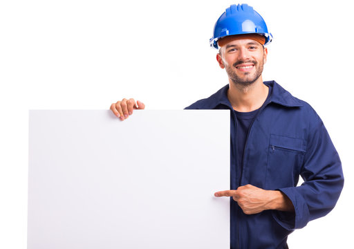 Smiling young worker pointing to a white placard ready for your text or product