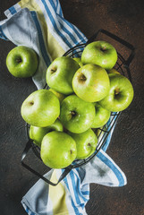 Fresh raw organic farm green apples in black metal basket, dark rusty background, copy space top view