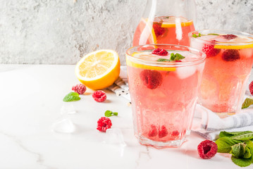 Summer refreshing drinks, fruit and berry raspberry mojito or lemonade with fresh mint, frozen raspberries, slices of lemon, ice, on a light background. copy space