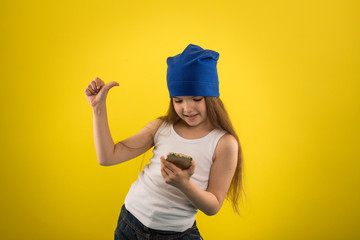 Beautiful caucasian girl posing on yellow isolated background in studio holding in hands mobile phone