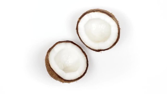 Top view of two ripe tropical coconut halves with yummy white pulp rotating on white isolated background. Healthy fresh tropical fruits. Loopable seamless cocos rotating