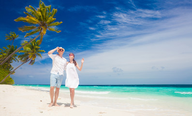 Fototapeta na wymiar happy young couple in white clothes walking by the beach. Maldives