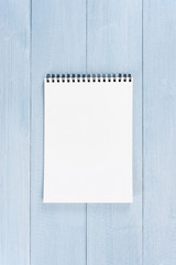 Blank sheet of opened notepad on the blue wooden table