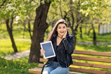 Young girl in the park with a tablet in hand.