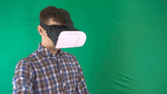 Man Play VR Glasses And Take Off Them At Geen Background. Virtual Reality Mask With Green Screen. Medium Shot