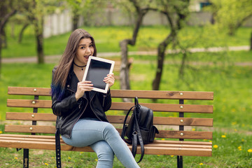Portrait of young girl holding digital tablet in the park