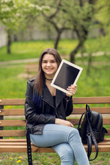 Fototapeta premium Portrait of young girl holding digital tablet in the park
