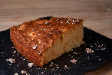 Apple pie tart on shale board with raisins, nuts and cinnamon is a vintage wooden background texture. Rustic style