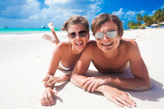 portrait of happy young couple with suncream dots at beach