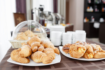 Fresh croissants on white plate. French traditional pastry. Breakfast in hotel smorgasbord.