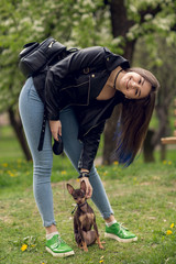 Young beautiful caucasian girl playing with dog russian toy terrier outdoors
