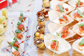 Delicious rolls canapes of eggplant and tomato. Tasty buffet table. Summer party outdoor. Catering concept