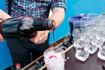 the bartender pours the syrup into the glass. Summer party outdoor.