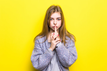 Naklejka premium Portrait of teenage girl with silence sign on yellow background
