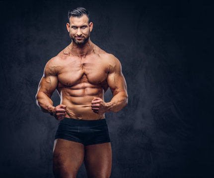 Portrait of a shirtless tall huge male with a muscular body with a stylish haircut and beard, in a underwear, posing in a studio.