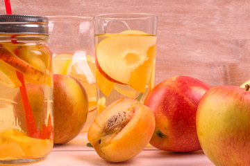 Cool apple-peach summer drink and ripe fresh fruit on a light background