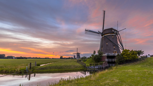 Three windmills in a row under beautiful sunset