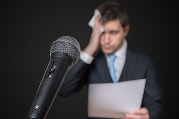 Microphone in front of a nervous man who is afraid of public speech and sweating.